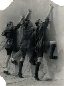 Trio de danseuses en costumes noirs adossées contre un mur fissuré lors d'une performance contemporaine par Sophie Caminade